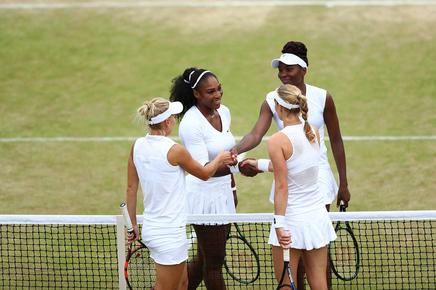 Serena and Venus Williams and Ekaterina Makarova and Elena Vesnina shake hands after their match. 